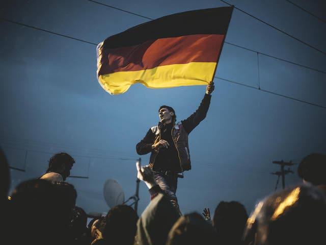 A Syrian refugee waves a German flag at a Pro-Merkel rally