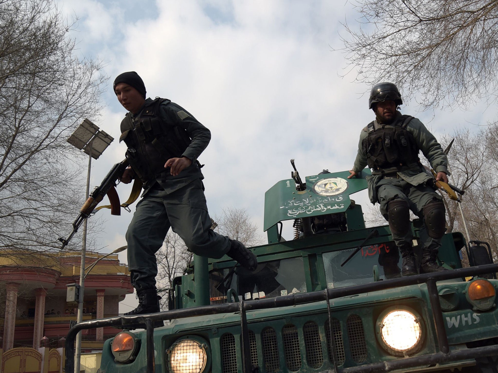 Afghan police officers leap into action after a military hospital attack on 8 March that left dozens dead