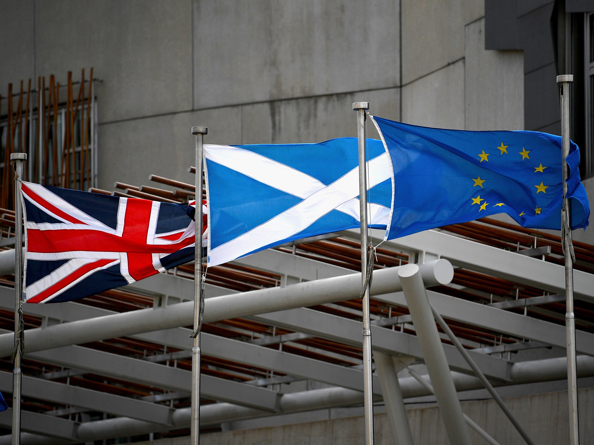 A Saltire, Union Jack and EU flags flutter in the wind outside the Scottish Parliament