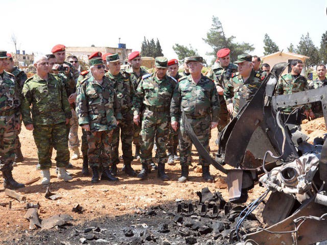 Syrian Armed Forces members survey damage at the Shayrat airfield in this handout released by the Syrian Arab News Agency