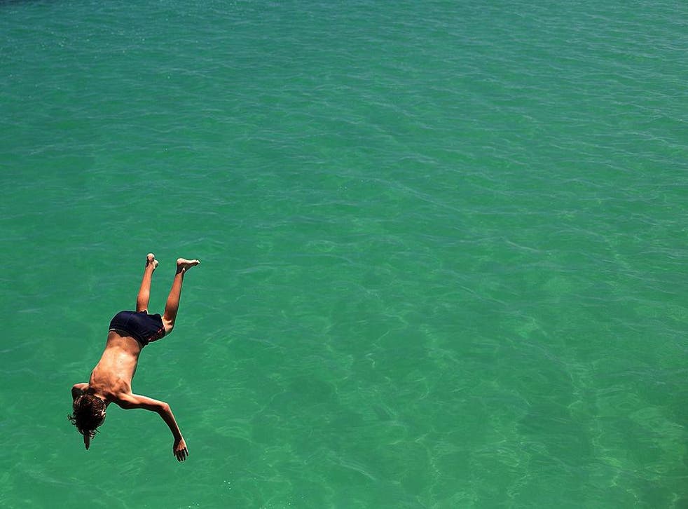 A teenager jumps from the jetty during a heat wave at Glenelg beach on 13 January, 2014 in Adelaide, Australia