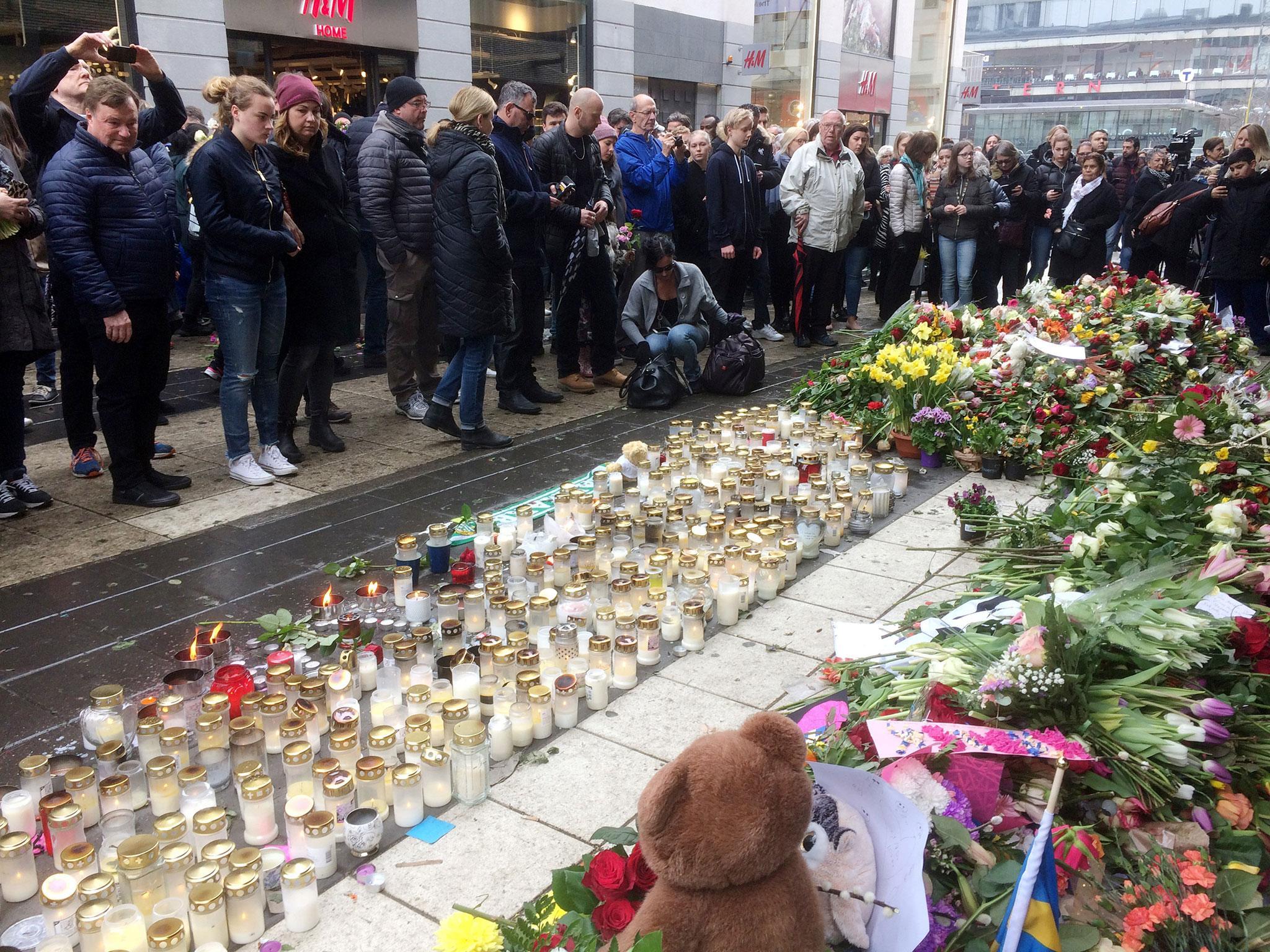 People gather in memorial next to the Ahlens department store following the attack in central Stockholm on Friday