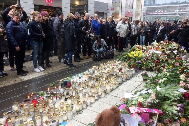 People look at flowers and candles next to the Ahlens department store following the attack in central Stockholm