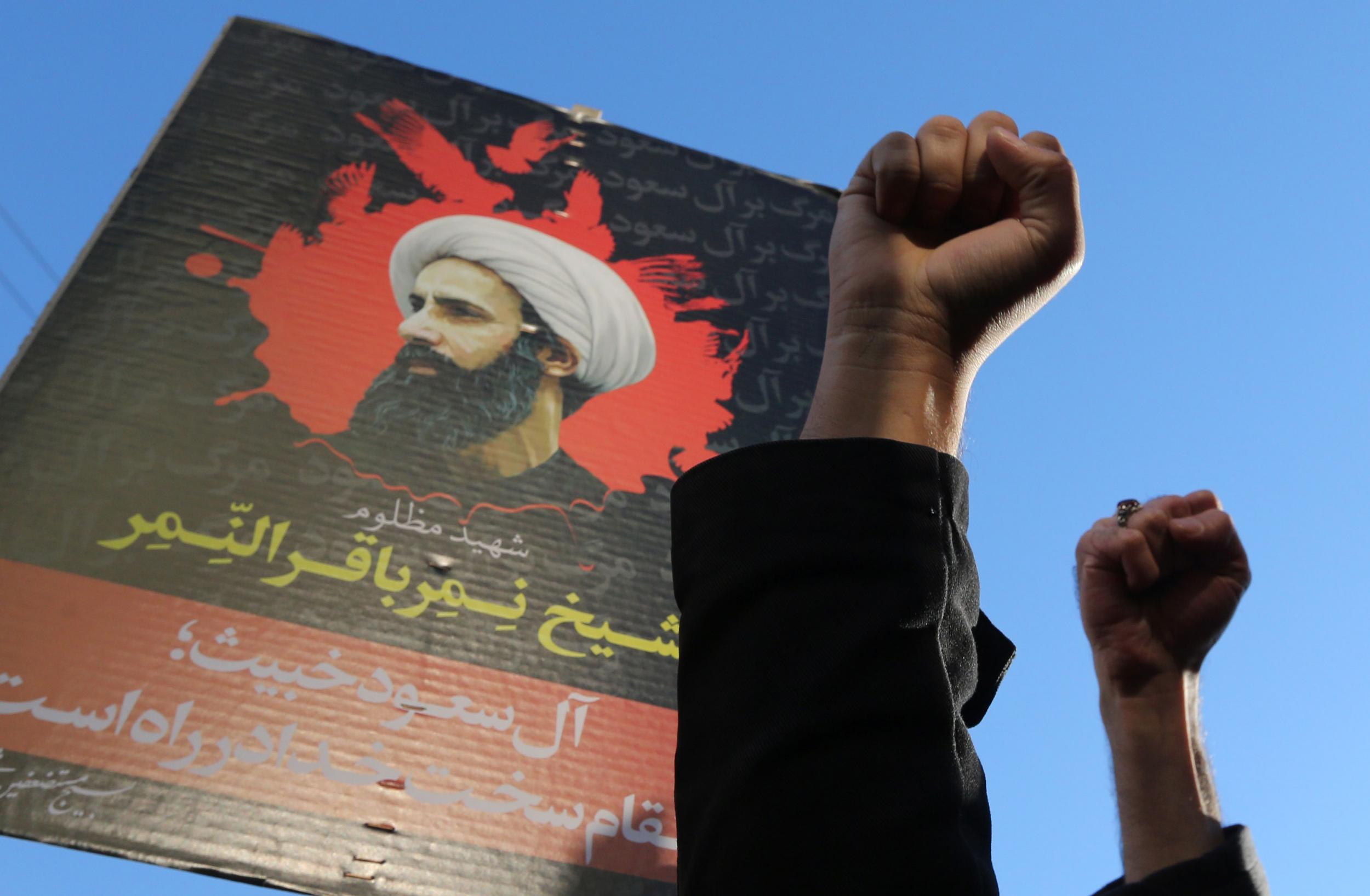 Protesters raise their fists in front of a portrait of prominent Shiite Muslim cleric Nimr al-Nimr during a demonstration against his execution by Saudi authorities, on January 3, 2016