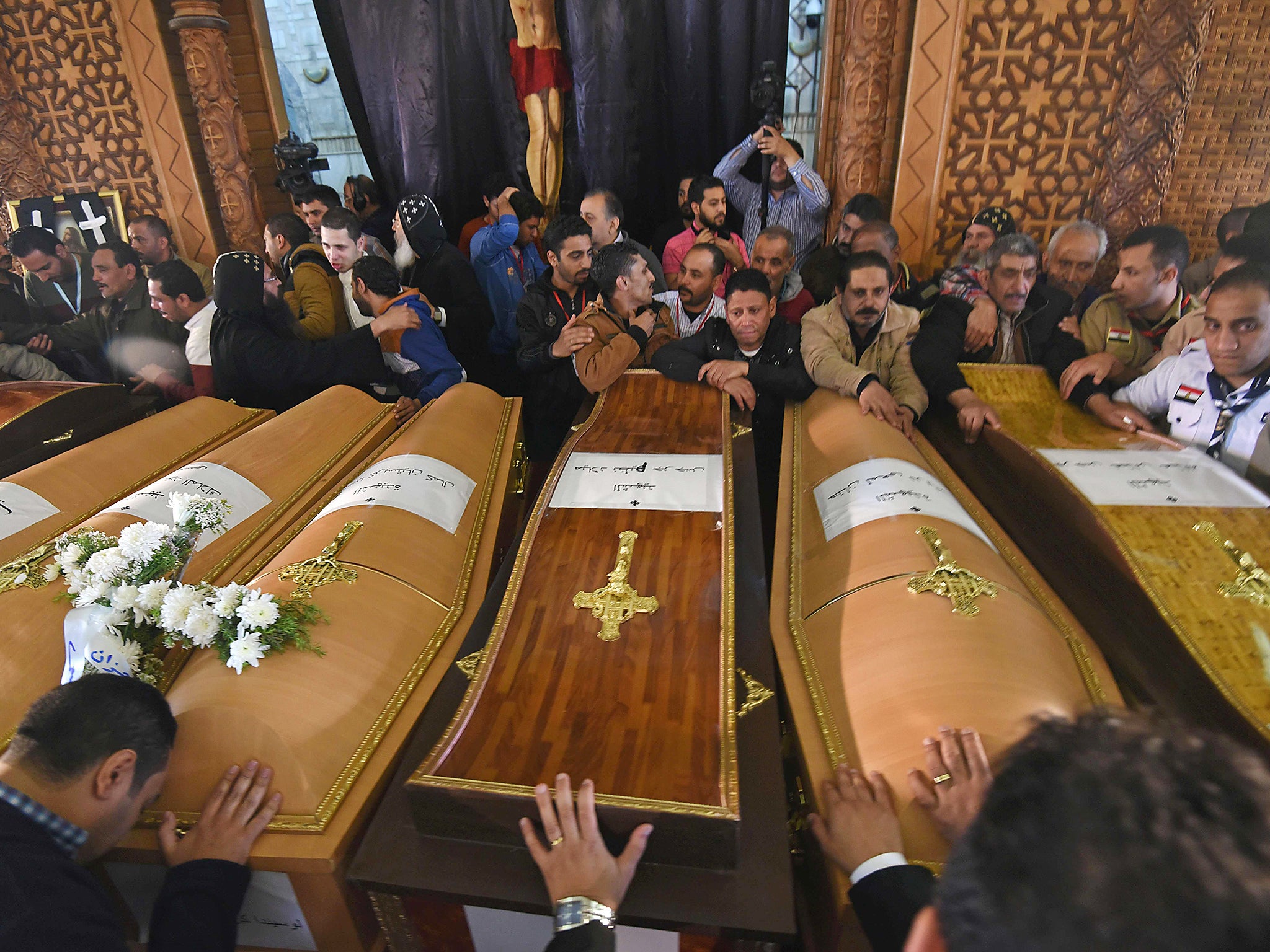 Mourners pray next to coffins of victims of the blast at the Coptic Christian Saint Mark's church in Alexandria