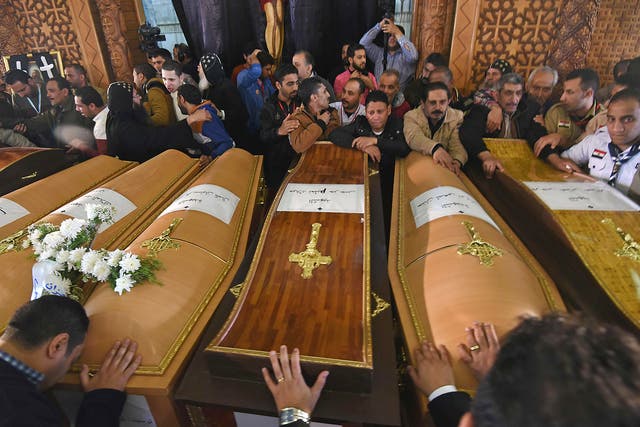 Mourners pray next to coffins of victims of the blast at the Coptic Christian Saint Mark's church in Alexandria 