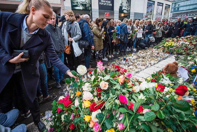 A woman lays flowers to commemorate the victims of Friday's terror attack at a makeshift memorial near the site where a truck drove into Ahlens department store in Stockholm, Sweden