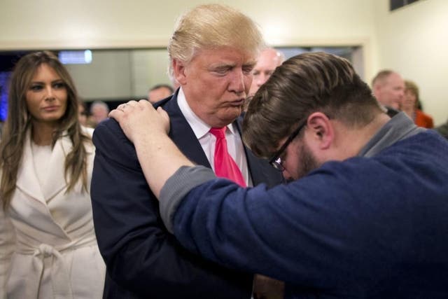 Pastor Joshua Nink, right, prays for Republican presidential candidate Donald Trump, as his wife, Melania, watches after a Sunday service at First Christian Church, in Council Bluffs, Iowa, in January 2016