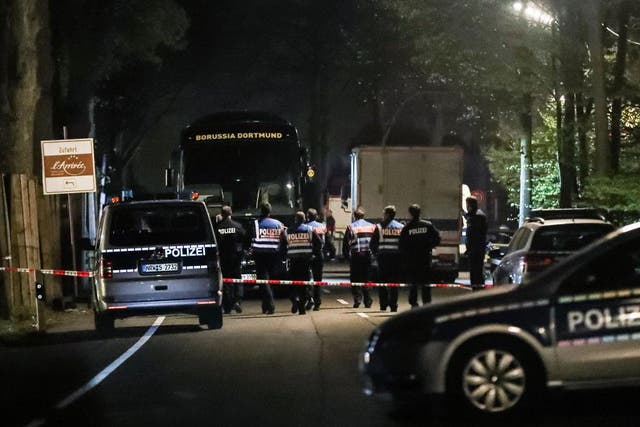 Investigators examine the Borussia Dortmund team bus, which was damaged in a bomb attack
