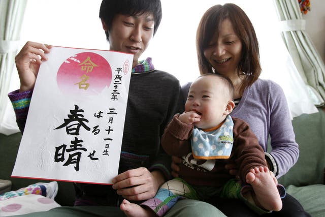 Proud parents Kenji and Hiromi Sato hold their son, Haruse, at their home in Minamisanriku