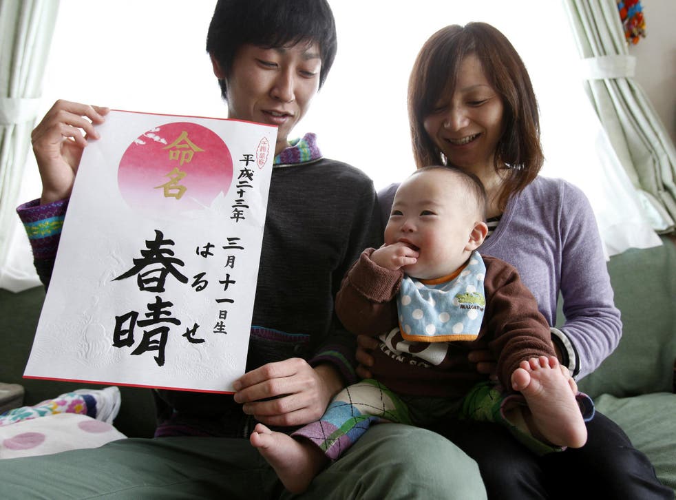 Proud parents Kenji and Hiromi Sato hold their son, Haruse, at their home in Minamisanriku