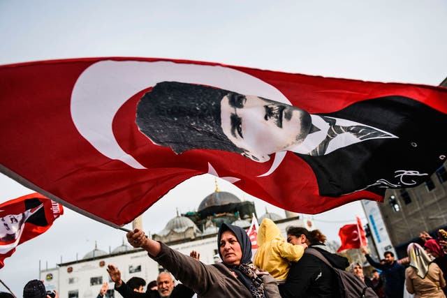 A Turkish woman supporting the 'No' vote in the upcoming constitutional referendum campaign waves a Turkish flag with a picture of modern Turkey's founder Mustafa Kemal Ataturk in front of Yeni Camii