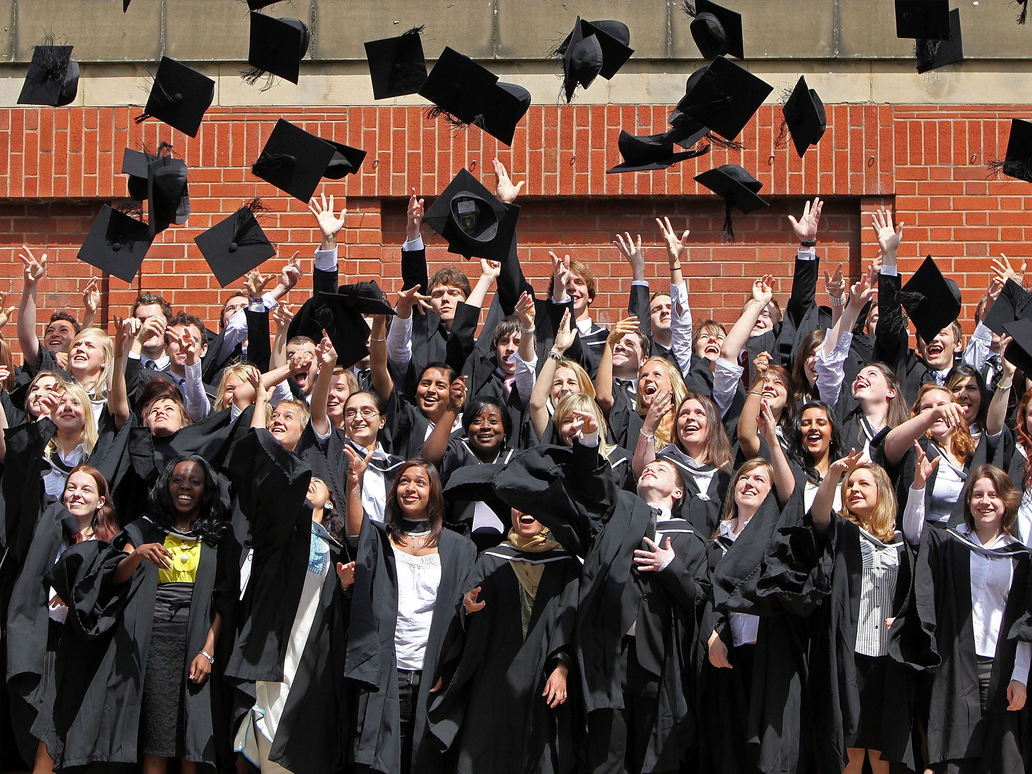 Students throw their mortarboards in the air during their graduation photograph at the University of Birmingham