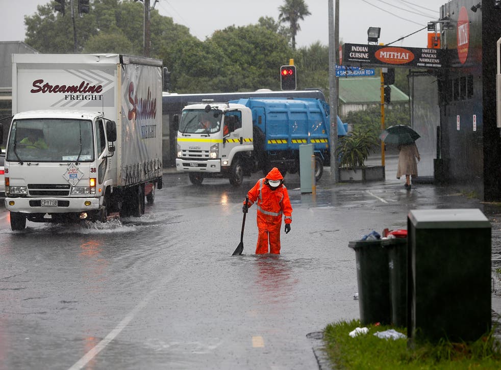 A worker tries to limit the impact of flooding in the New Zealand's largest city, Auckland, as the storm moves down the country