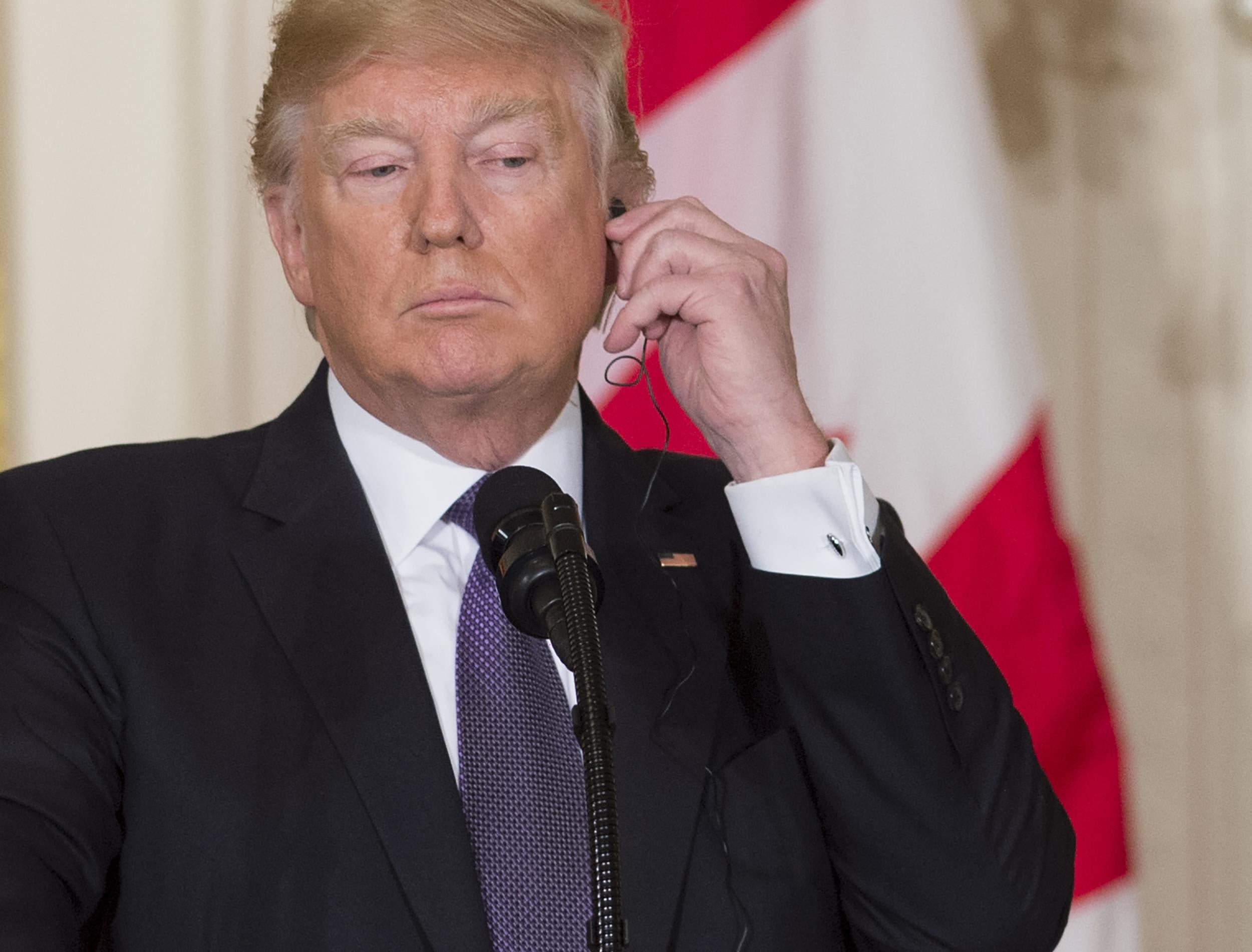 US President Donald Trump listens to an earpiece during a joint press conference with Canadian Prime Minister Justin Trudeau