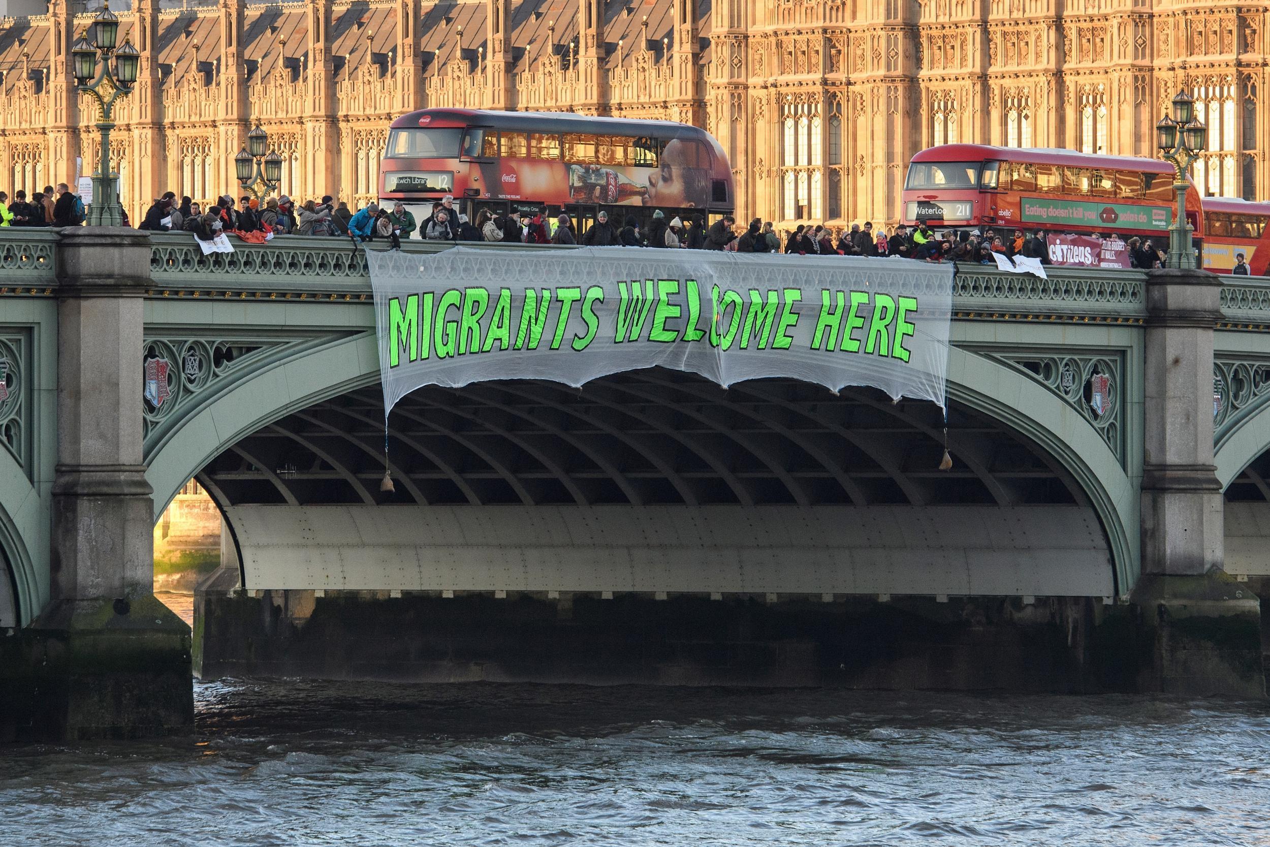 A banner reading 'Migrants Welcome Here' is unfurled on Westminster Bridge on January 20, 2017 in London