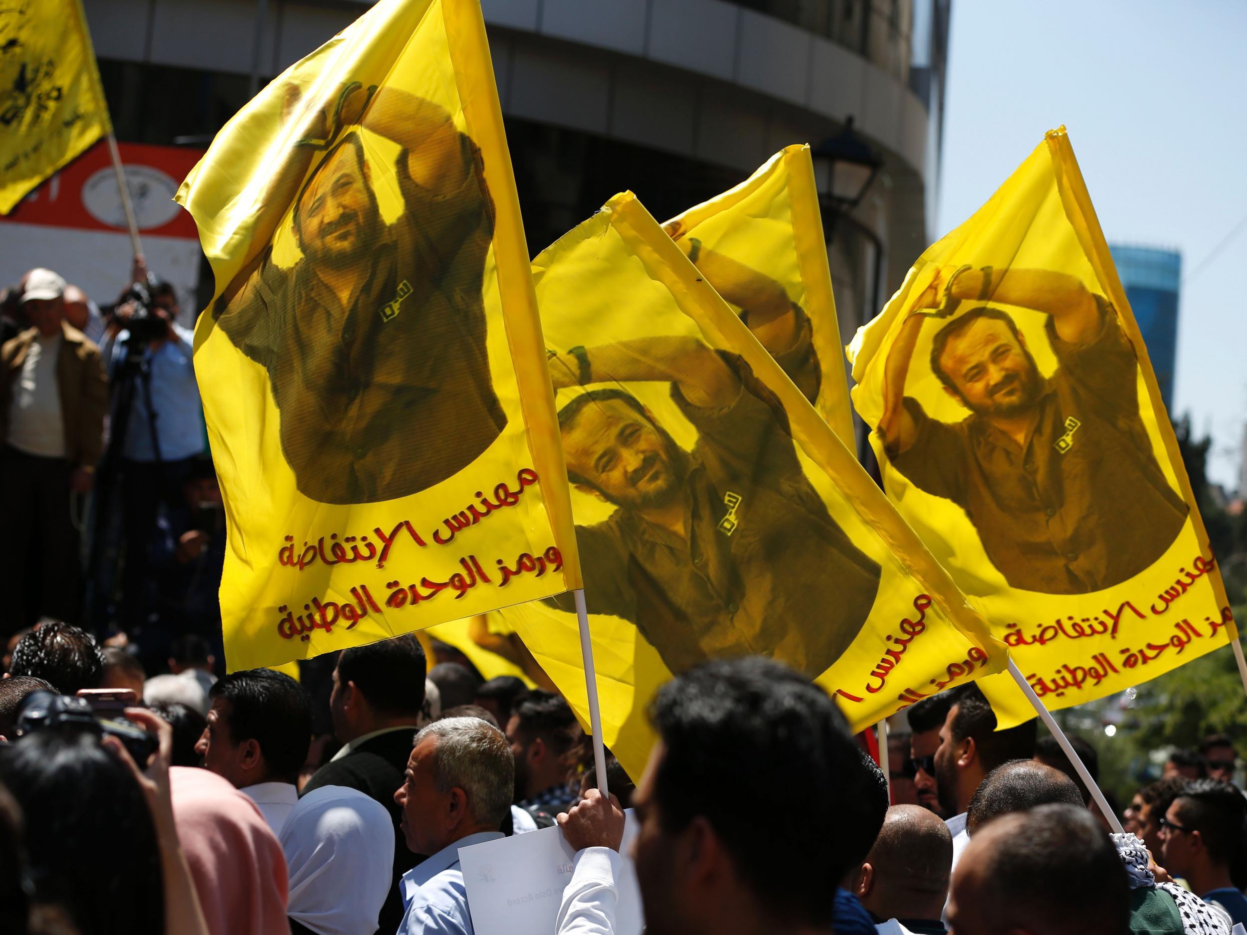 Protesters in Ramallah waving flags bearing a portrait of Marwan Borghouti