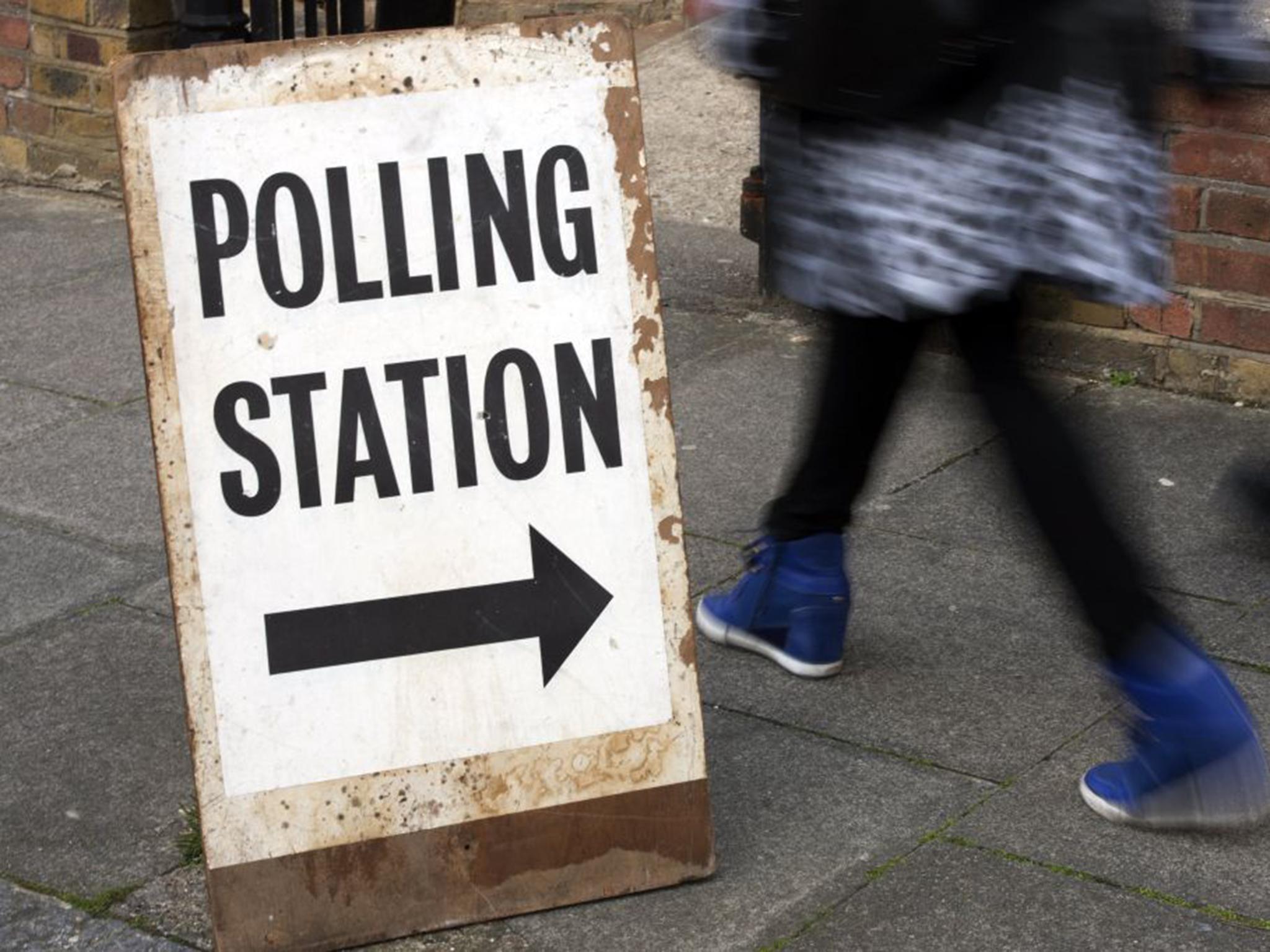 People pass a polling station sign in Brixton in 2015