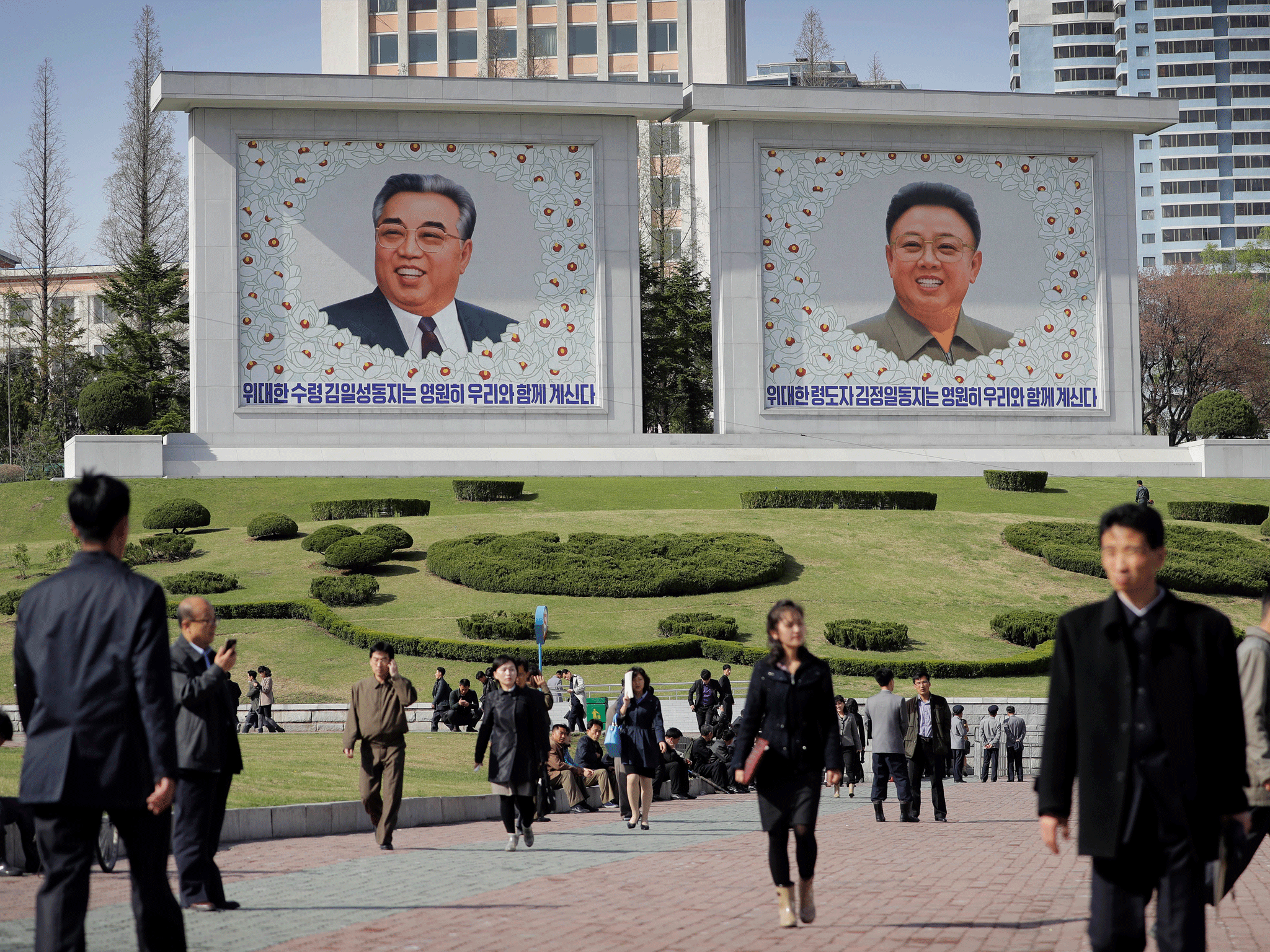 North Koreans in central Pyongyang, where portraits of the late leaders, Kim Il-sung, left, and Kim Jong-il, are seen in the background
