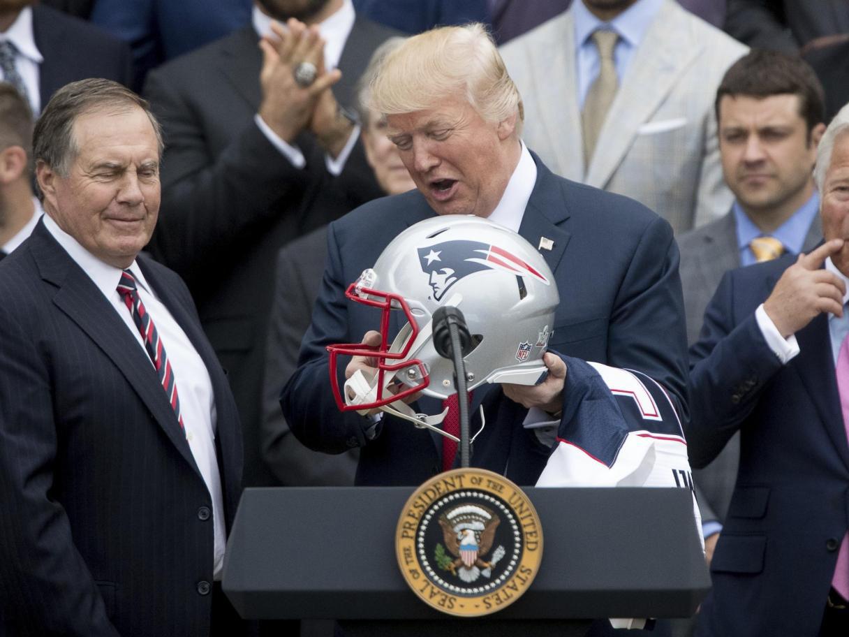 President Donald Trump holds a New England Patriots football helmet and jersey during a ceremony on the South Lawn of the White House