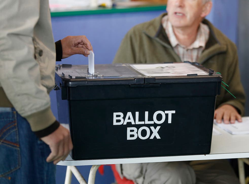 A voter places his vote slip into a ballot box at a polling station