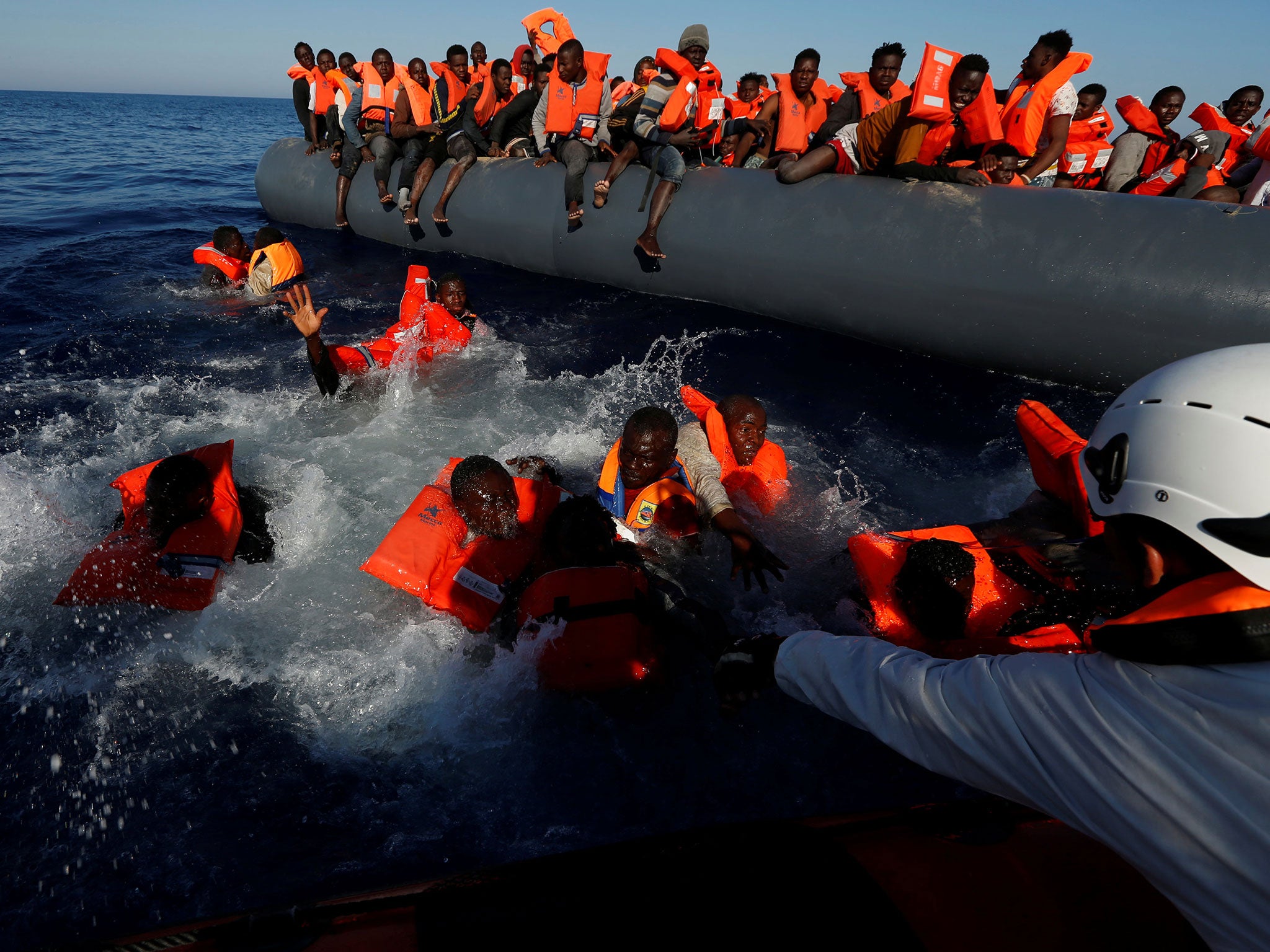 Migrants try to stay afloat after falling off their rubber dinghy during a rescue operation by Moas off the coast of Zawiya in Libya