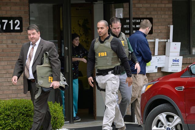 FBI agents leave the office of Dr Fakhruddin Attar at the Burhani Clinic in Livonia after searching for documents