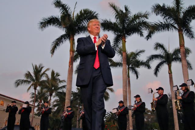 President Trump applauds a marching band at the Trump International Golf Club in West Palm Beach, Florida