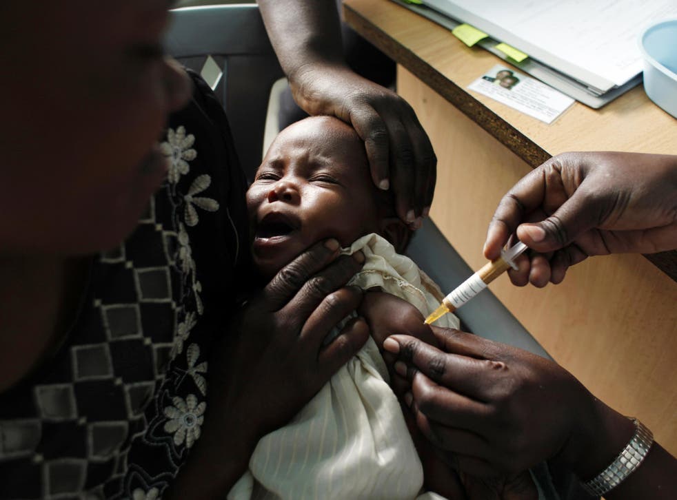 A mother holds her baby receiving a new malaria vaccine as part of a trial at the Walter Reed Project Research Center in Kombewa in western Kenya