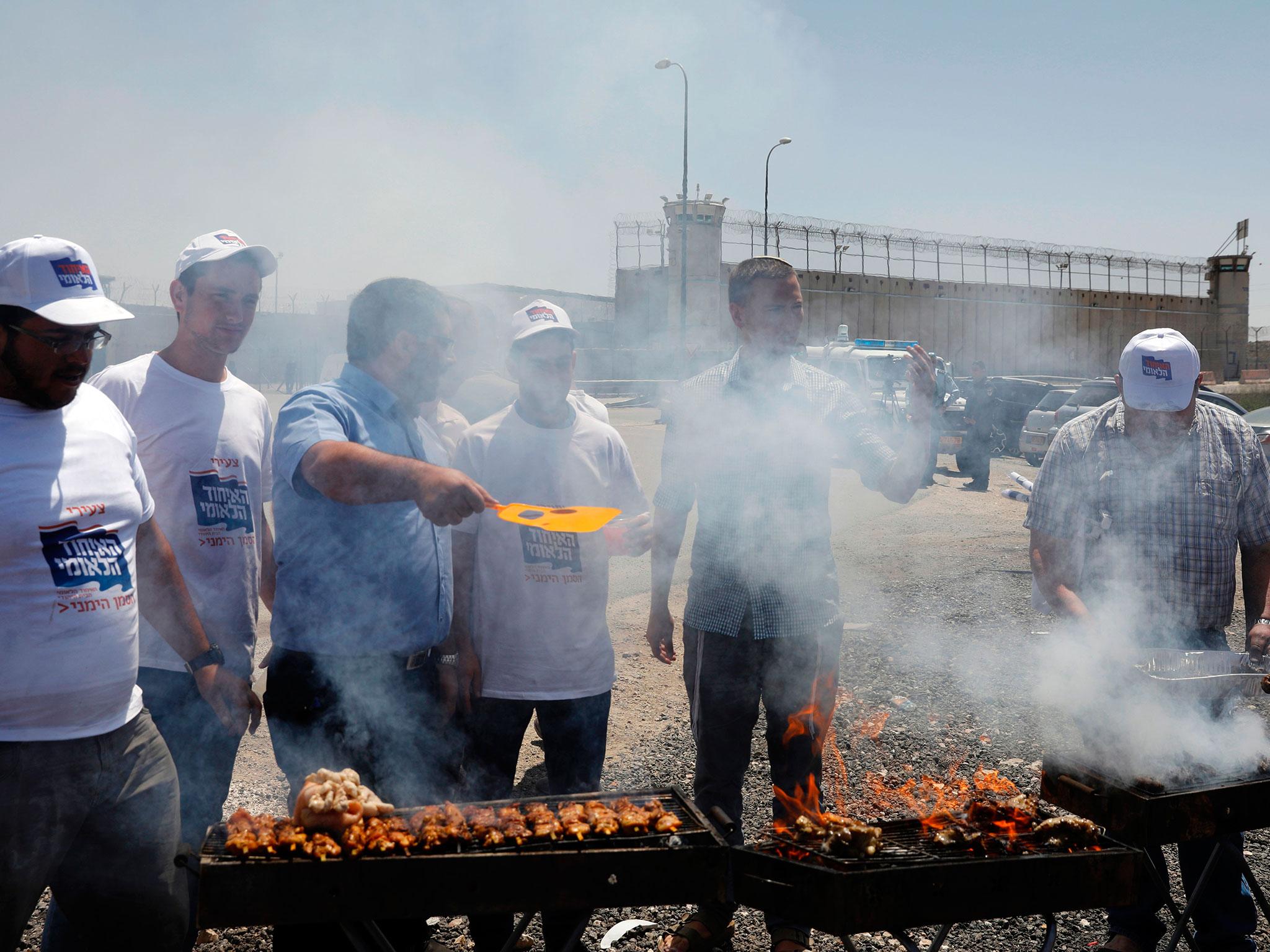 Israeli right-wing activists hold a barbecue outside Ofer military prison in the occupied West Bank, where a number of Palestinian prisoners are on a hunger strike