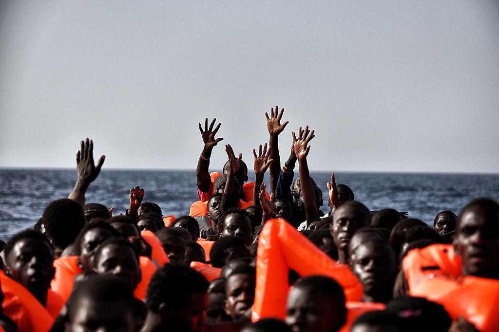 People gesture for help as they drift in the Mediterranean Sea some 20 nautical miles north off the coast of Libya in October 2016