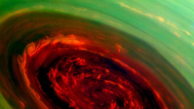 In this handout image released on April 30, 2013 by NASA, the spinning vortex of Saturn's north polar storm is seen from NASA's Cassini spacecraft on November 27, 2012 in the Saturnian system of space. The false-color image of the storm resembles a red rose surrounded by green foliage which was made by using a combination of spectral filters sensitive to wavelengths of near-infrared light at a distance of approximately 261,000 miles from Saturn