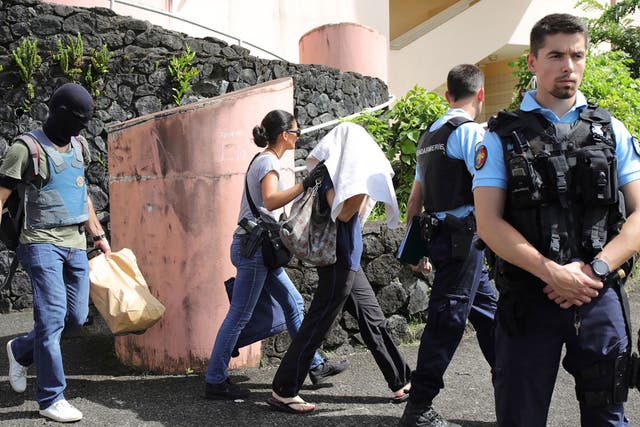 French gendarmes and police officers escort a person on the French island of Reunion, after a man suspected of being a radicalised Islamist shot two officers on 27 April