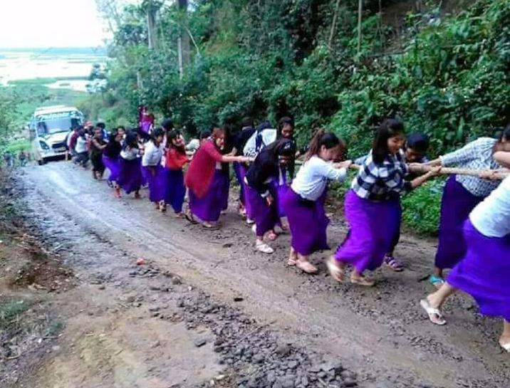 Indian schoolgirls drag a broken down bus uphill in Manipur
