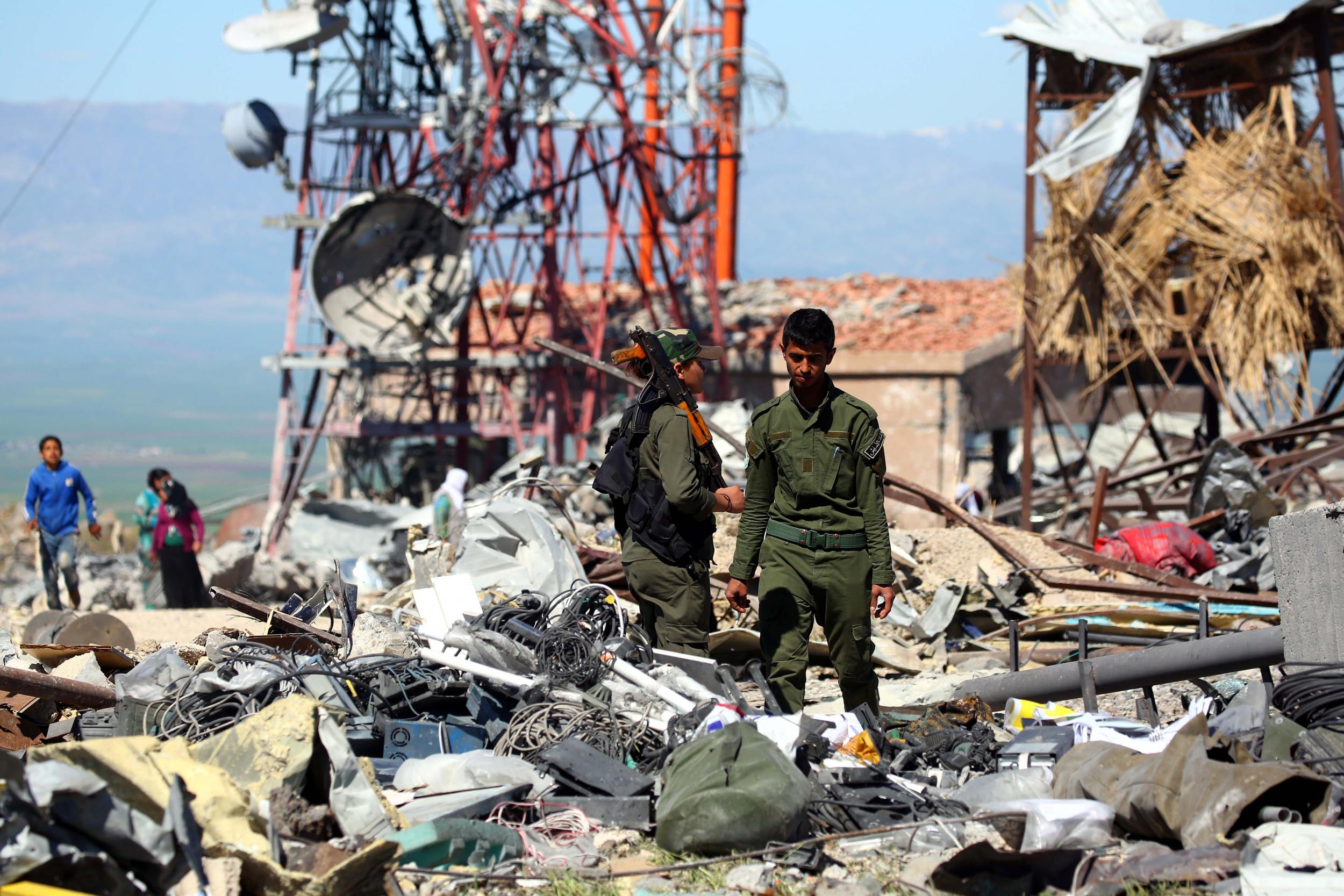 The aftermath of a Turkish airstrike is inspected by members of the Kurdish People's Protection Units (YPG), seen by the United States as a key ally in the fight against Isis