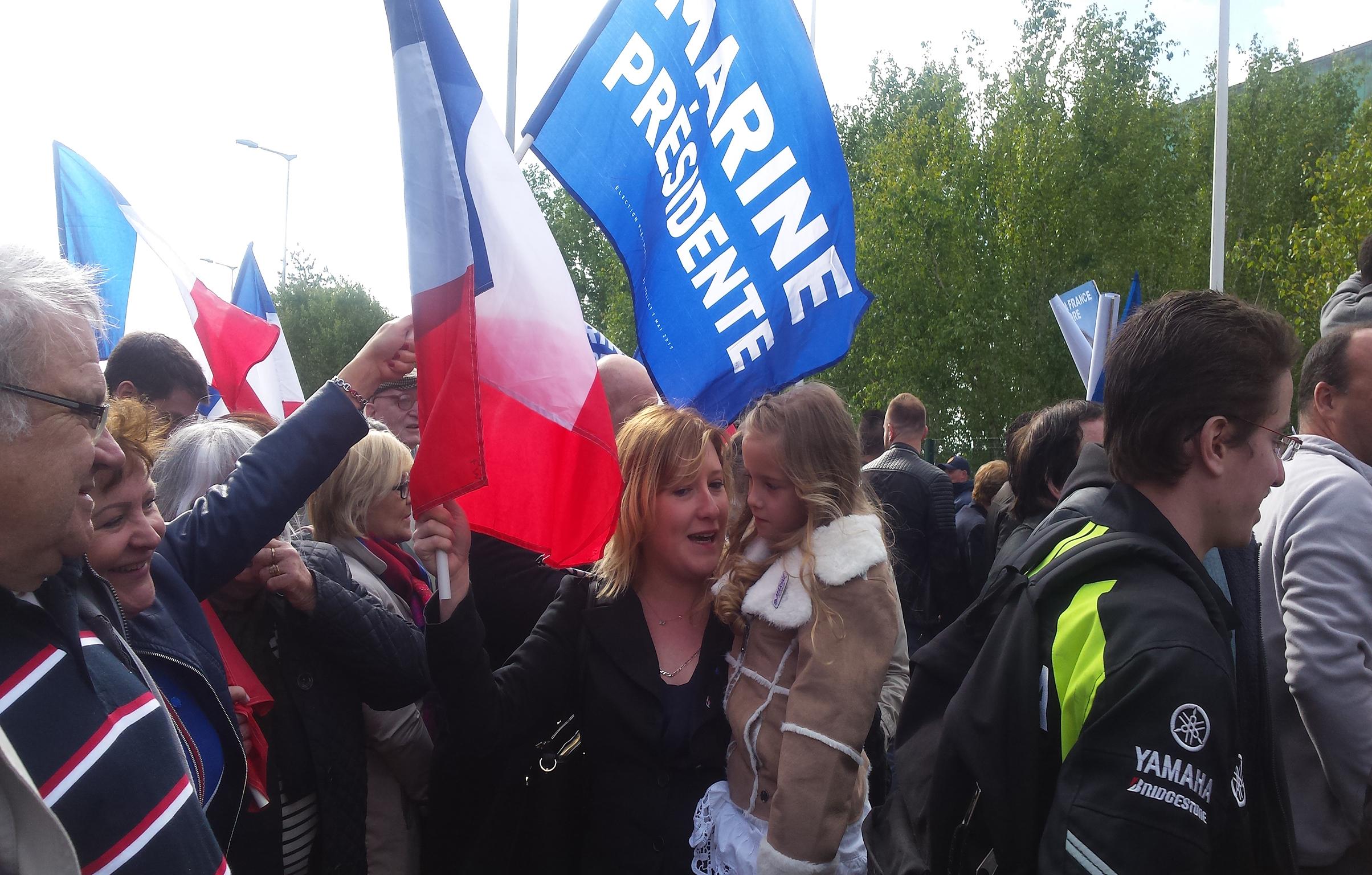 A Marine Le Pen supporter holds her daughter at Marine Le Pen's rally
