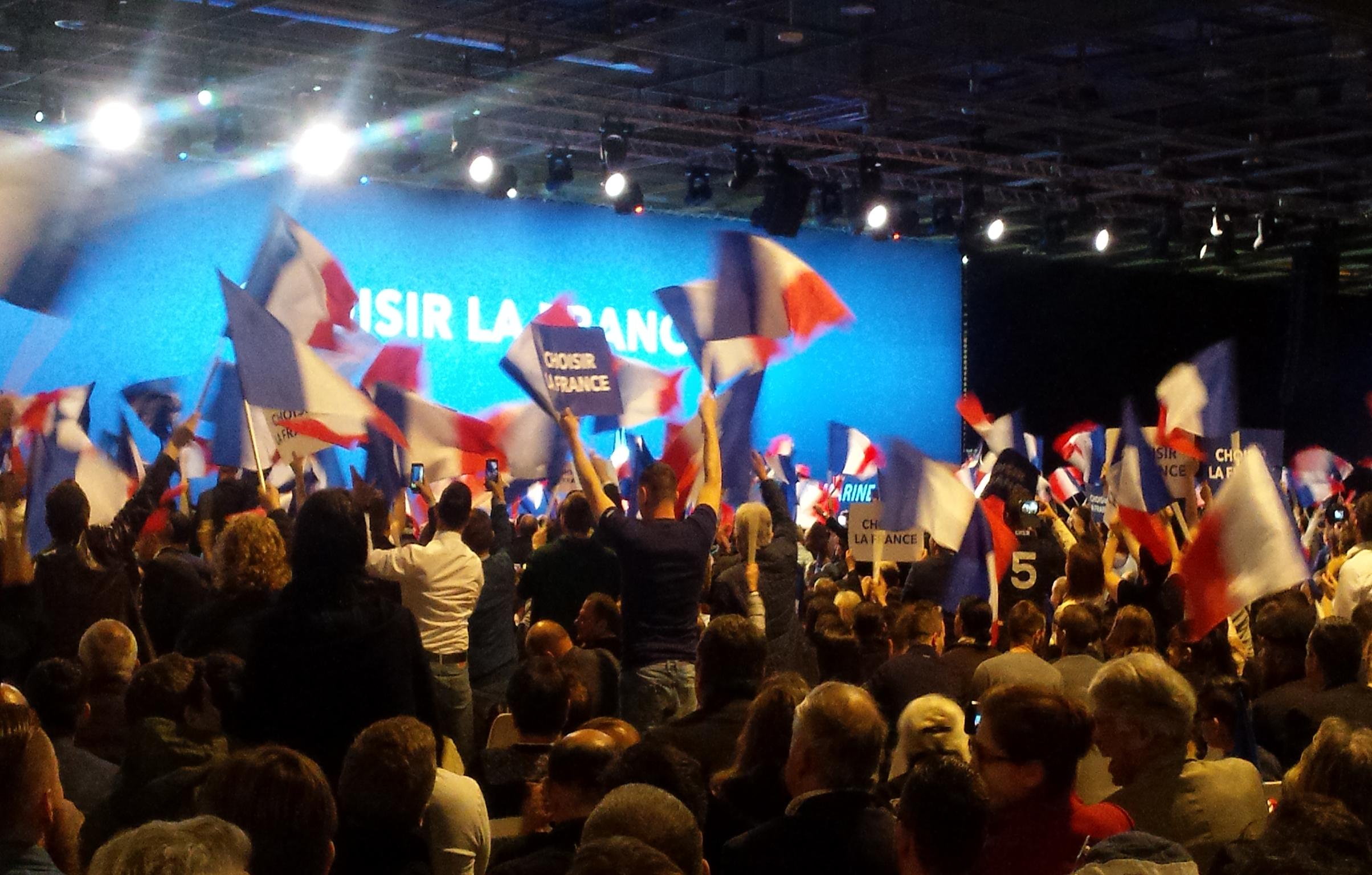 Marine Le Pen supporters cheer and wave their flags