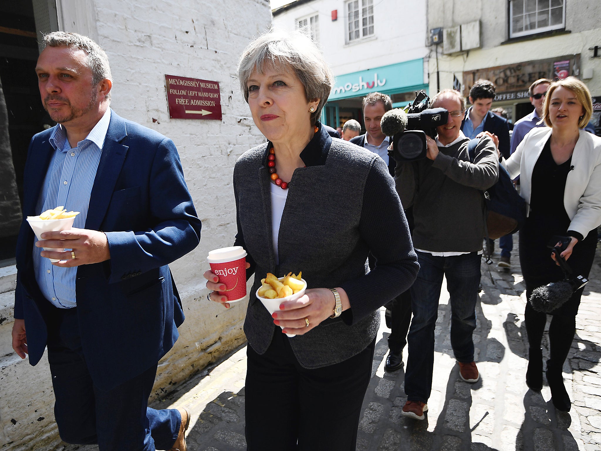Britain's Prime Minister Theresa May is followed by journalists as she carries some chips during a campaign stop in Mevagissey, Cornwall