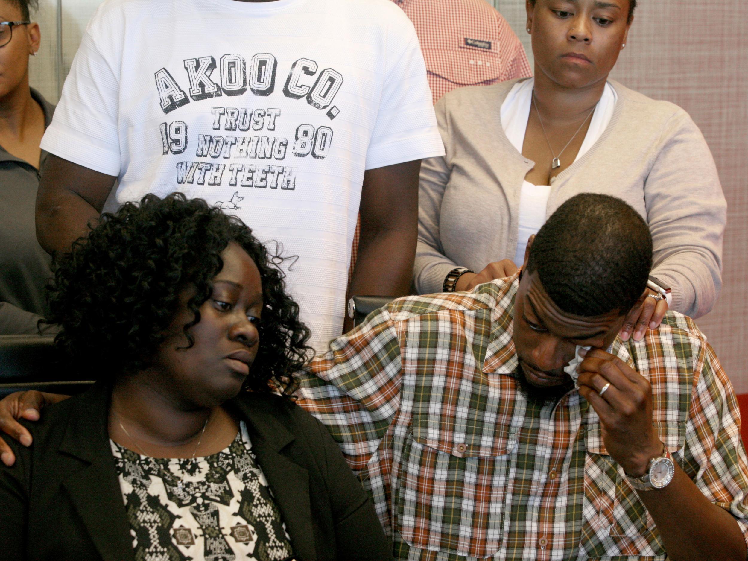 Odell Edwards wipes away tears as he sits with his wife, Charmaine Edwards, listening to their attorney Lee Merritt talking about the death of their son, Jordan