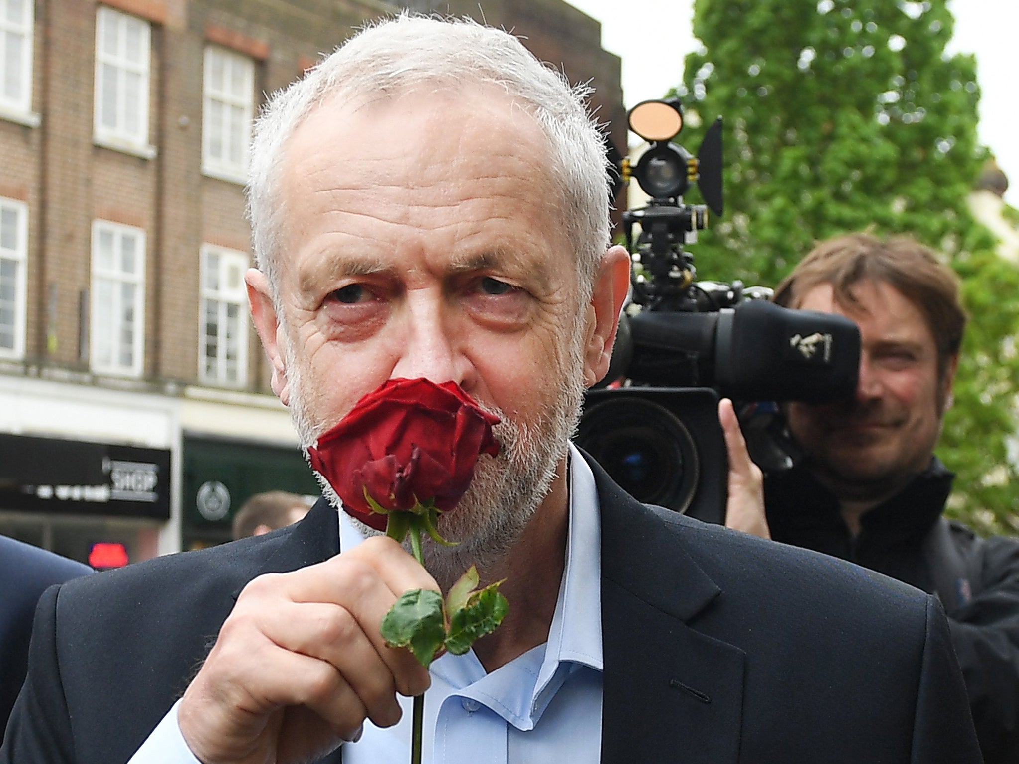 British Labour leader Jeremy Corbyn smells a red rose alongside Mohammed Yasin, the Labour Party general election candidate for Bedford and Kempston while on the campaign trail in Bedford