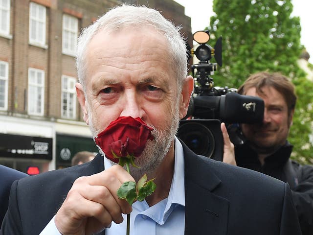 British Labour leader Jeremy Corbyn smells a red rose alongside Mohammed Yasin, the Labour Party general election candidate for Bedford and Kempston while on the campaign trail in Bedford