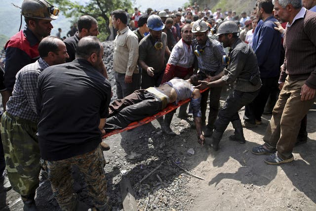 Miners and rescue personnel carry away an injured worker after the incident near Azadshahr