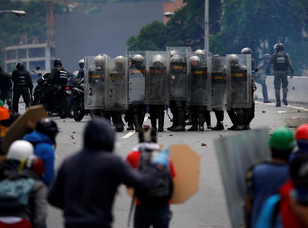 Riot police take position while clashing with opposition supporters rallying against President Nicolas Maduro in Caracas