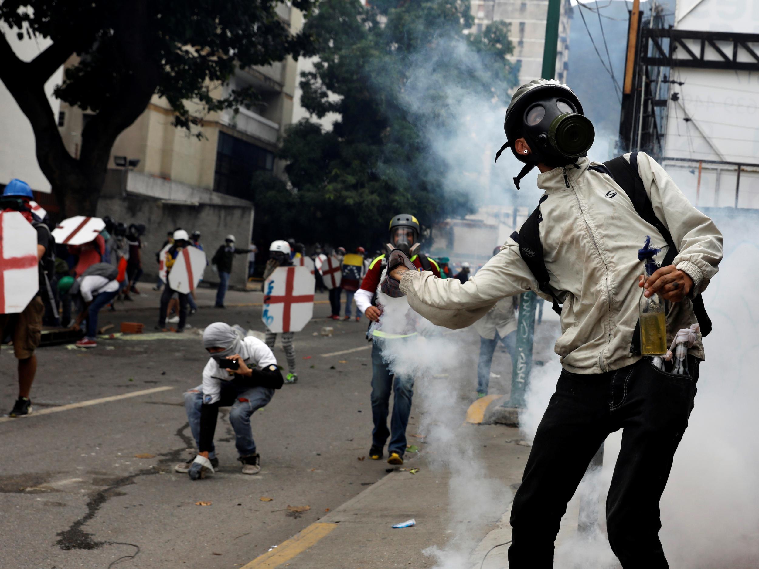 Opposition supporters brandishing shields and smoke bombs on the streets of Caracas