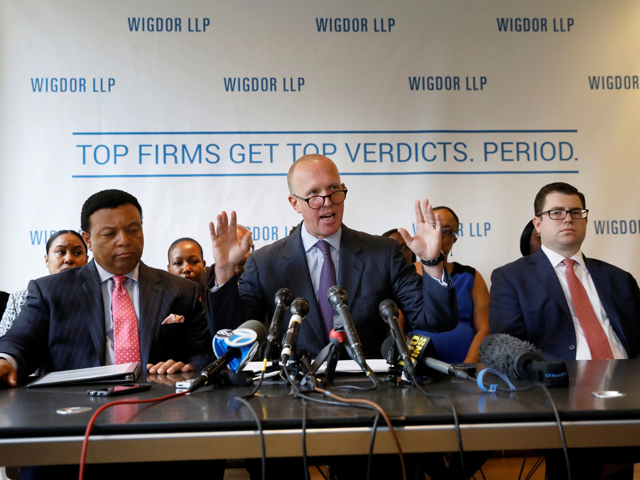 Douglas Wigdor raises his hands as he addresses the media with Fox News host Kelly Wright (L), one of those involved in the race discrimination class-action lawsuit