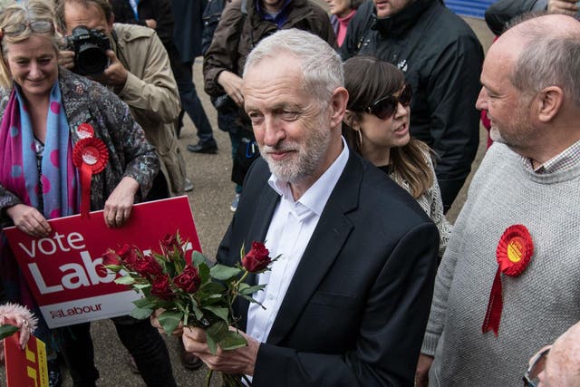 Labour Party leader Jeremy Corbyn holds red roses given to him by activists and supporters as he visits a local shopping arcade on May 4, 2017 in Oxford, England