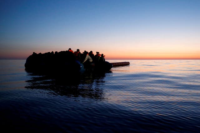 Refugees on a rubber dinghy await rescue at dawn in the central Mediterranean