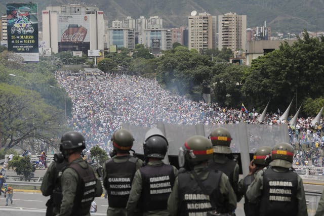 Bolivarian National Guards stand on a highway overlooking an anti-government march