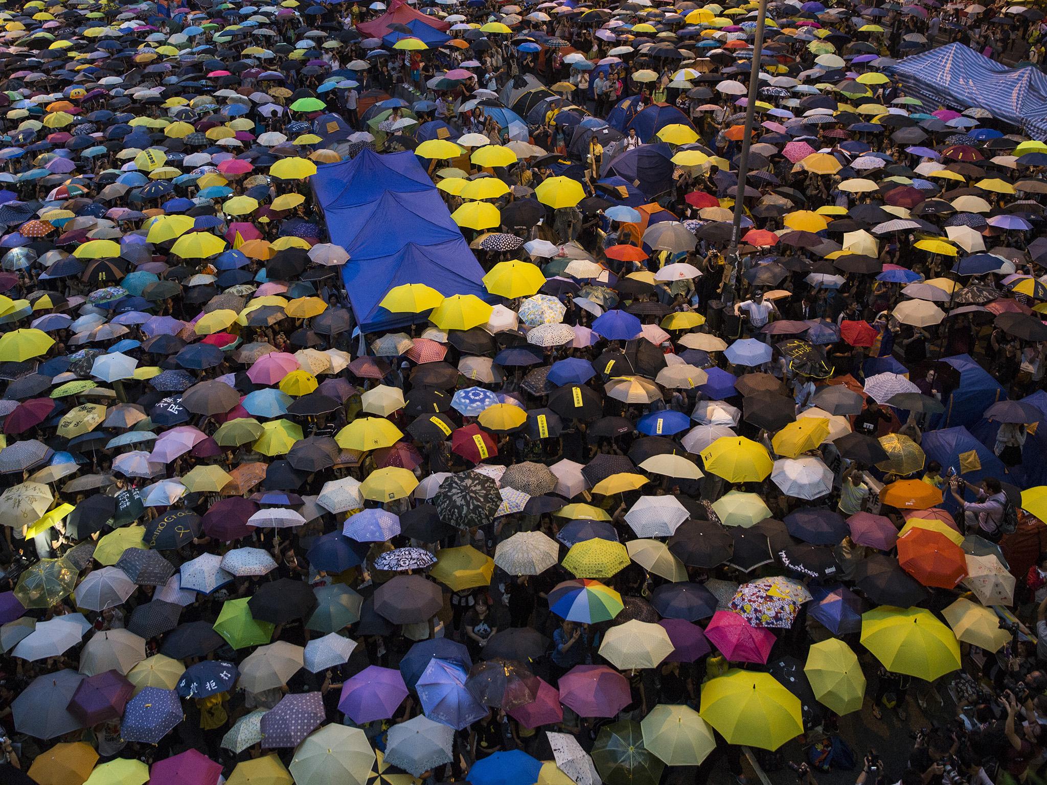 Umbrellas are opened as tens of thousands come to the main protest site one month after the Hong Kong police used tear gas to disperse protesters