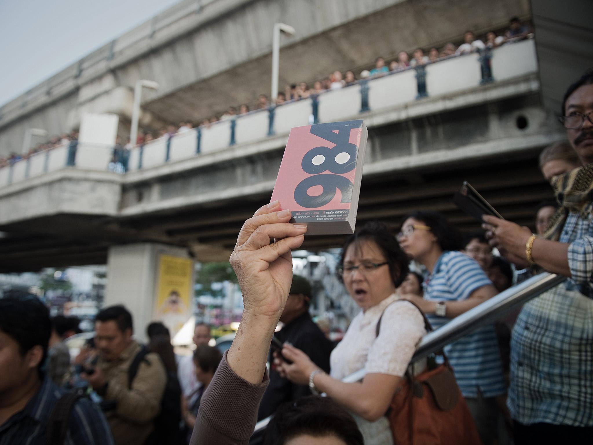 A demonstrator holds up George Orwell's book 1984 during a rally outside the Art and Cultural centre in Bangkok